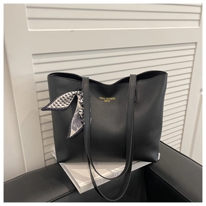 Close-up of black leather tote bag with geometric silk scarf and golden lettering
