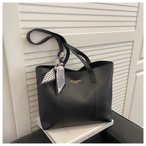 Detail of black leather tote bag with gold lettering and decorative geometric silk scarf