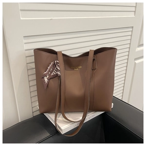 Detail of a brown tote bag with textured faux leather finish and a printed silk scarf
