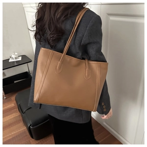 Close-up of a brown leather tote bag with vertical stitching and draped bottom design
