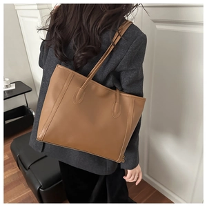 Detailed view of light brown tote bag showing smooth matte leather texture and stitching