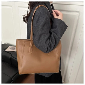 Detail of the caramel brown leather tote bag with elegant stitching and long shoulder straps