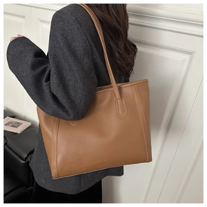 Detail of a large brown faux leather tote bag with slim shoulder straps for daily commute