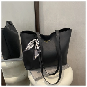 Detail of black faux leather tote bag with gold lettering and decorative silk scarf
