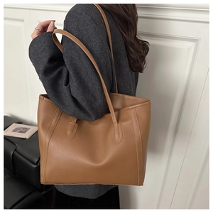 Brown faux leather tote bag showing side view proportions on a model with stitching detail