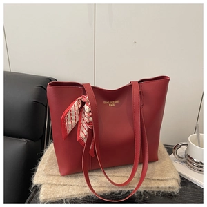 Macro shot of dark red synthetic leather tote bag with a decorative silk scarf on the handle