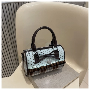 Detailed close-up of bow knot and star pattern on vintage plaid cylinder bag