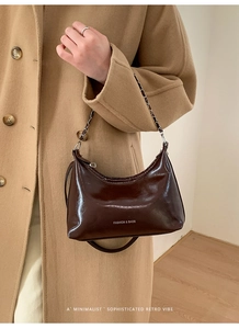 Dettaglio borsa hobo in vernice marrone scuro lucida con scritte bianche e catena