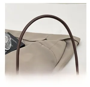 Dettaglio della borsa baguette retrò in pelle marrone con cuciture sulla tracolla