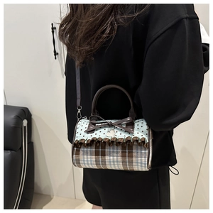 Detail of plaid pleated bow handbag featuring star pattern and heart pendant