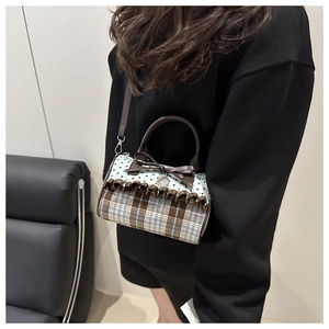 Detail of canvas plaid shoulder bag featuring brown bow and heart metal pendant charm