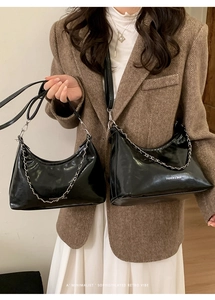 Dettaglio della borsa hobo nera lucida con catena d'argento su una modella in blazer