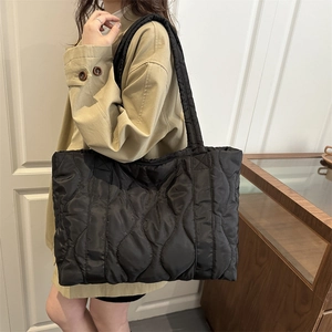 Large black quilted puffer tote bag in minimalist wave stitch design for women