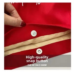 Detail of premium silver magnetic closure on a red canvas tote bag with white embroidery