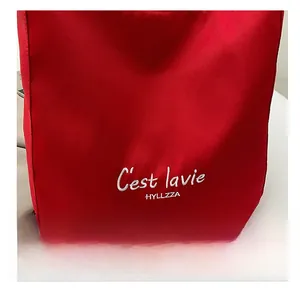 Detailed view of white letter embroidery on a red canvas tote bag for a modern look