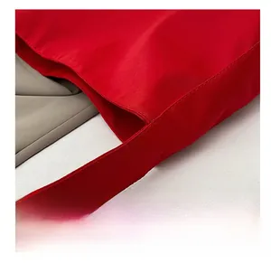 Detailed close-up of tight stitching on a large red nylon tote bag shoulder strap