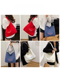 Detail of minimalist canvas tote bags in red, blue and white with C'est la vie text design