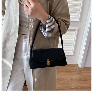 Dettaglio di una borsa baguette nera vintage con chiusura a scatto dorata sulla tracolla