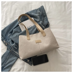 Detail of linen tote bag with contrast faux leather handles and rectangular patch