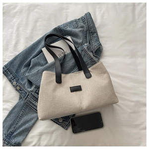 Detail of oatmeal canvas tote bag with black leather strap and rectangular accent patch