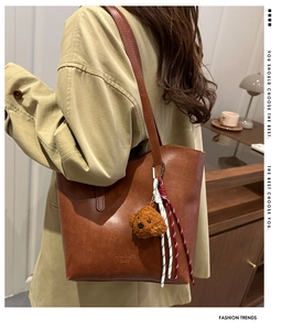 Detail of vintage brown tote bag with cute bear charm and woven rope decoration