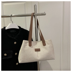 Détail d'un cabas en toile crème minimaliste avec garniture et poignée en cuir marron