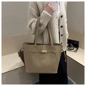 Detail of beige leather tote bag with golden lock and adjustable drawstring closure