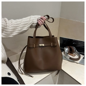 Detail of coffee brown leather bucket bag featuring gold metal buckle and carry handle