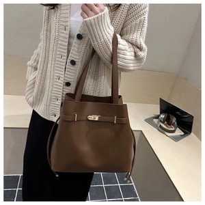 Detail of dark brown matte tote bag featuring gold buckle and decorative side drawstrings