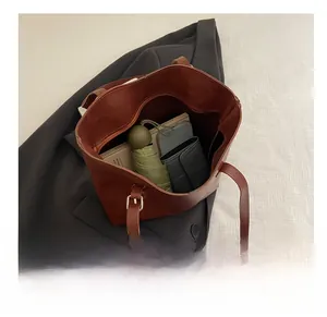 Brown leather tote bag showing large capacity for umbrella, wallet, and books