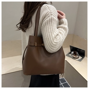 Classic dark brown leather tote bag with side drawstring details on a female model