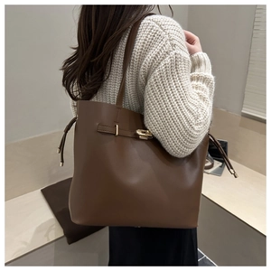 Detail of caramel leather bucket bag with gold hardware and side drawstring accents