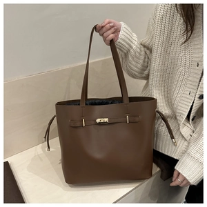 Close-up of deep brown tote bag with vintage golden metal buckle and drawstring lining