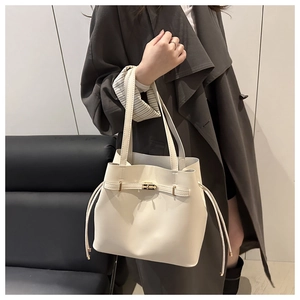 Detail of cream white bucket bag featuring a gold twist lock and smooth leather texture