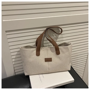 Close-up of linen tote bag with brown leather handles on a minimalist indoor setup