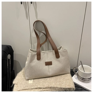 Detailed close-up of linen tote bag with contrast leather strap on a soft beige blanket