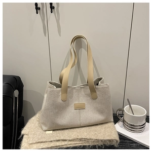 Detail of linen tote bag with brown leather handles and rectangular leather patch