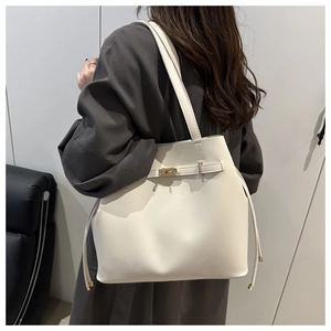 Detail of cream leather bucket bag with gold buckle and drawstring on a shoulder strap