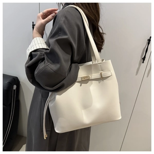 Detail of cream white tote bag with golden twist lock showing shoulder strap and side profile