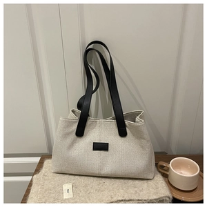 Macro shot of off-white tote bag texture and black contrast logo tag on wooden desk
