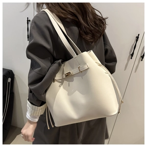 Close-up of golden metal lock and drawstring detail on off-white leather bucket tote bag