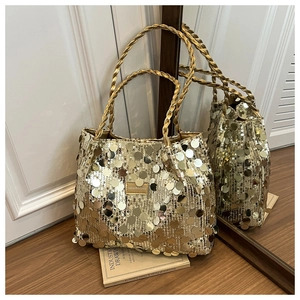 Detail of gold sequin tote bag with woven handles and fashion logo plaque on the side