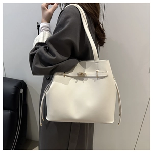 Detail of creamy white leather bucket bag showing golden twist lock and drawstring design