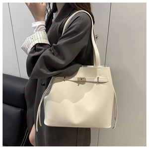 Side view of cream white bucket bag with golden lock and spacious leather design