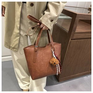 Détail d'un sac cabas marron vintage avec un joli pendentif chiot en peluche attaché