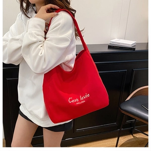 Detail showing red canvas tote bag with white C'est lavie script print on shoulder strap