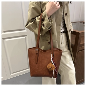 Detail of vintage brown PU leather bucket bag with plush charm and striped ribbon accent