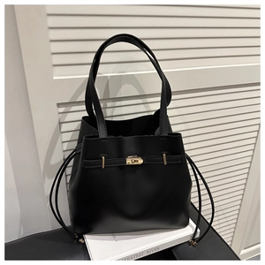 Detail of black leather bucket bag featuring a gold twist-lock and structured handles