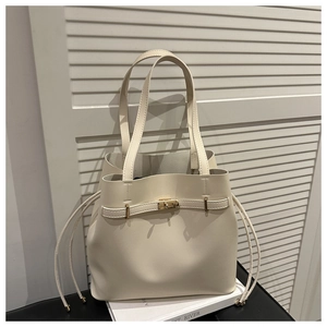 Detail of cream bucket bag with gold twist lock and drawstring on white books
