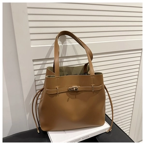 Detail view of brown leather bucket bag with metal twist lock and drawstring liner bag